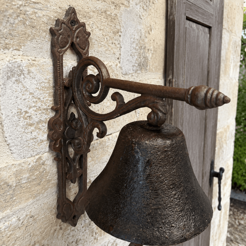 Campana de puerta de hierro fundido instalada sobre una fachada de piedra