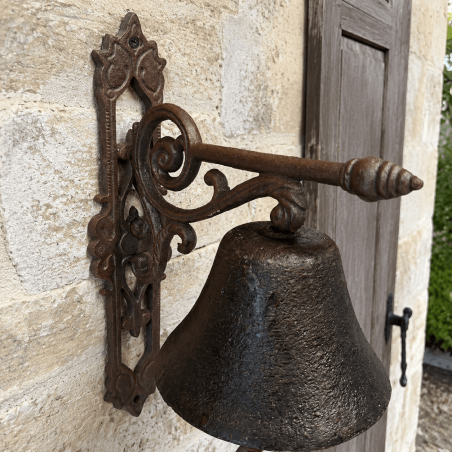 Campana de puerta de hierro fundido instalada sobre una fachada de piedra