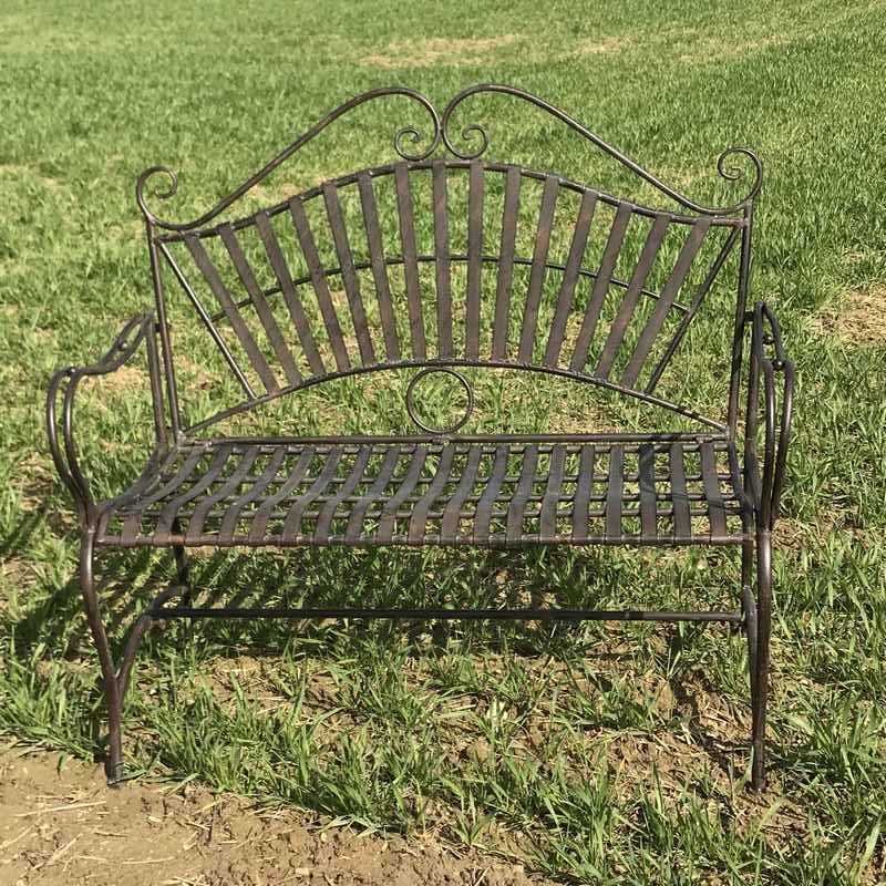 Banco de jardín de hierro forjado con arabescos, ambientado