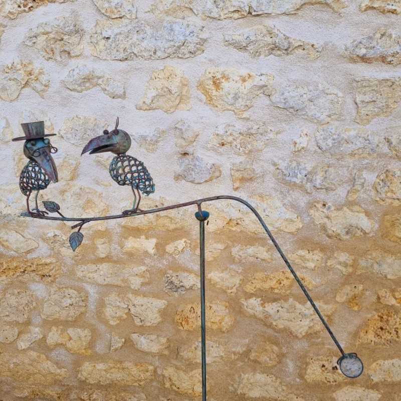 Mobile décoratif en métal avec oiseaux, chapeau et lunettes.