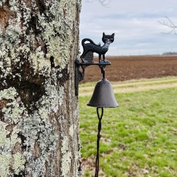 Campana decorativa con gato negro junto a una entrada