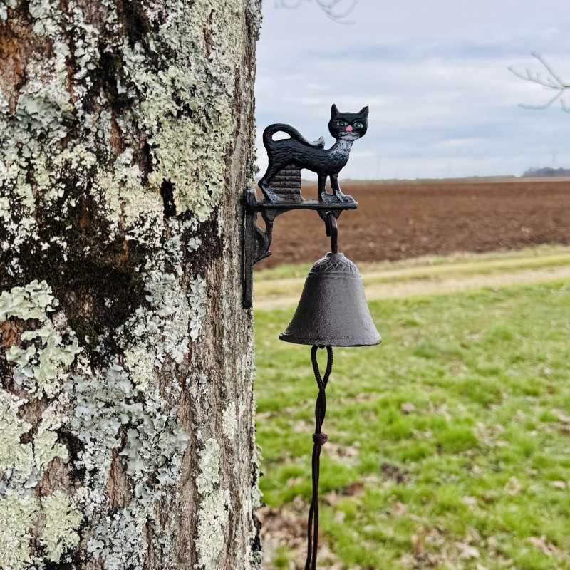 Campana decorativa con gato negro junto a una entrada