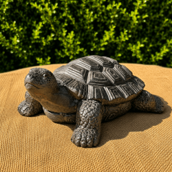 Tortuga decorativa efecto piedra instalada entre las plantas