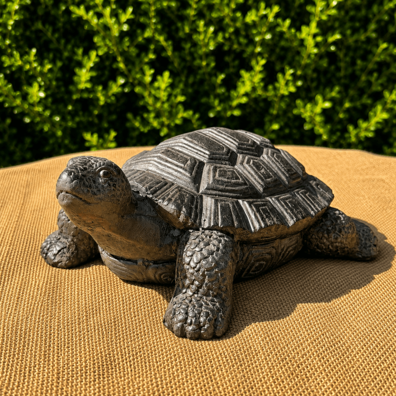 Tortuga decorativa efecto piedra instalada entre las plantas
